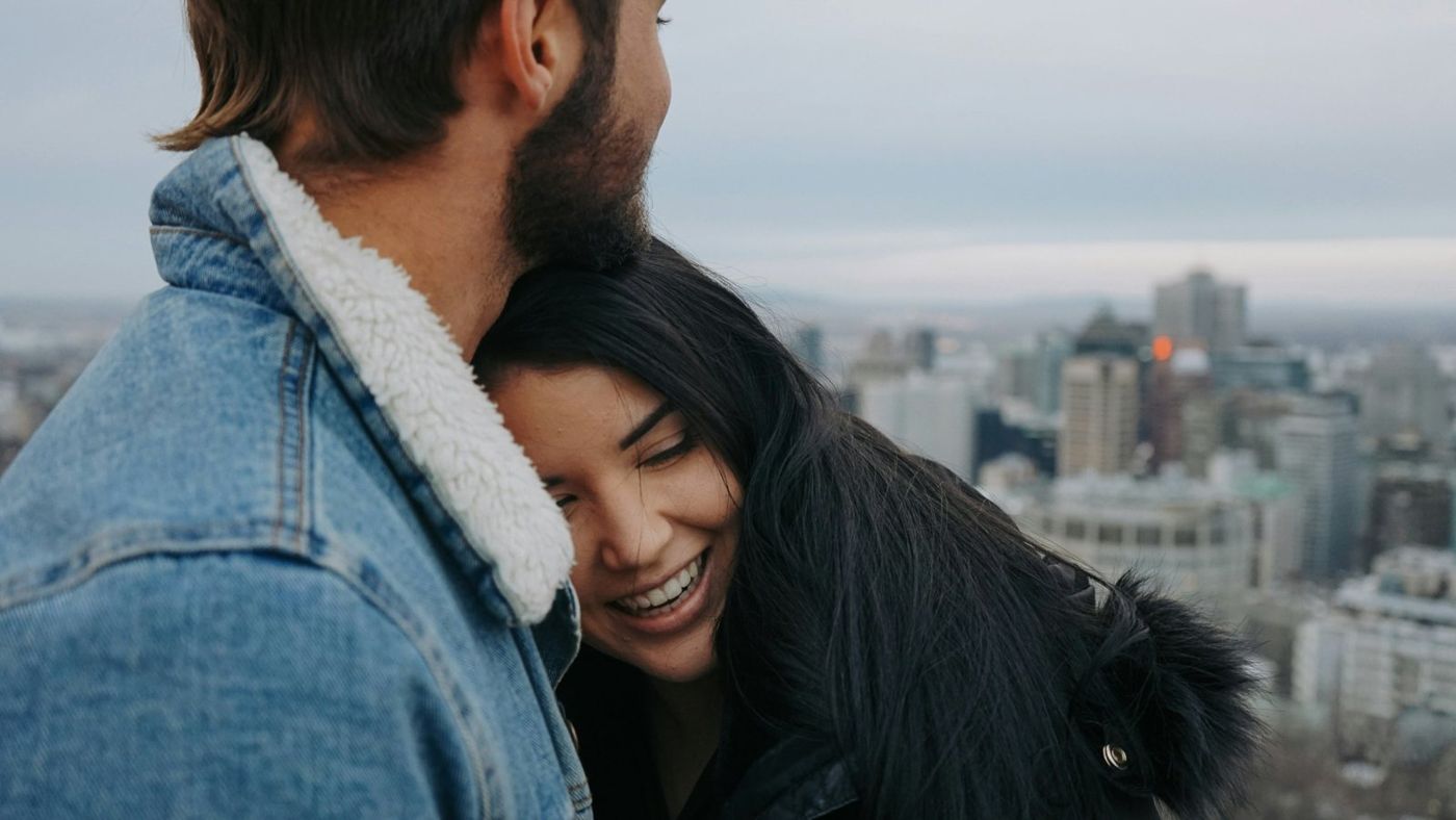 Un couple souriant sur un belvédère, avec Montréal en arrière-plan